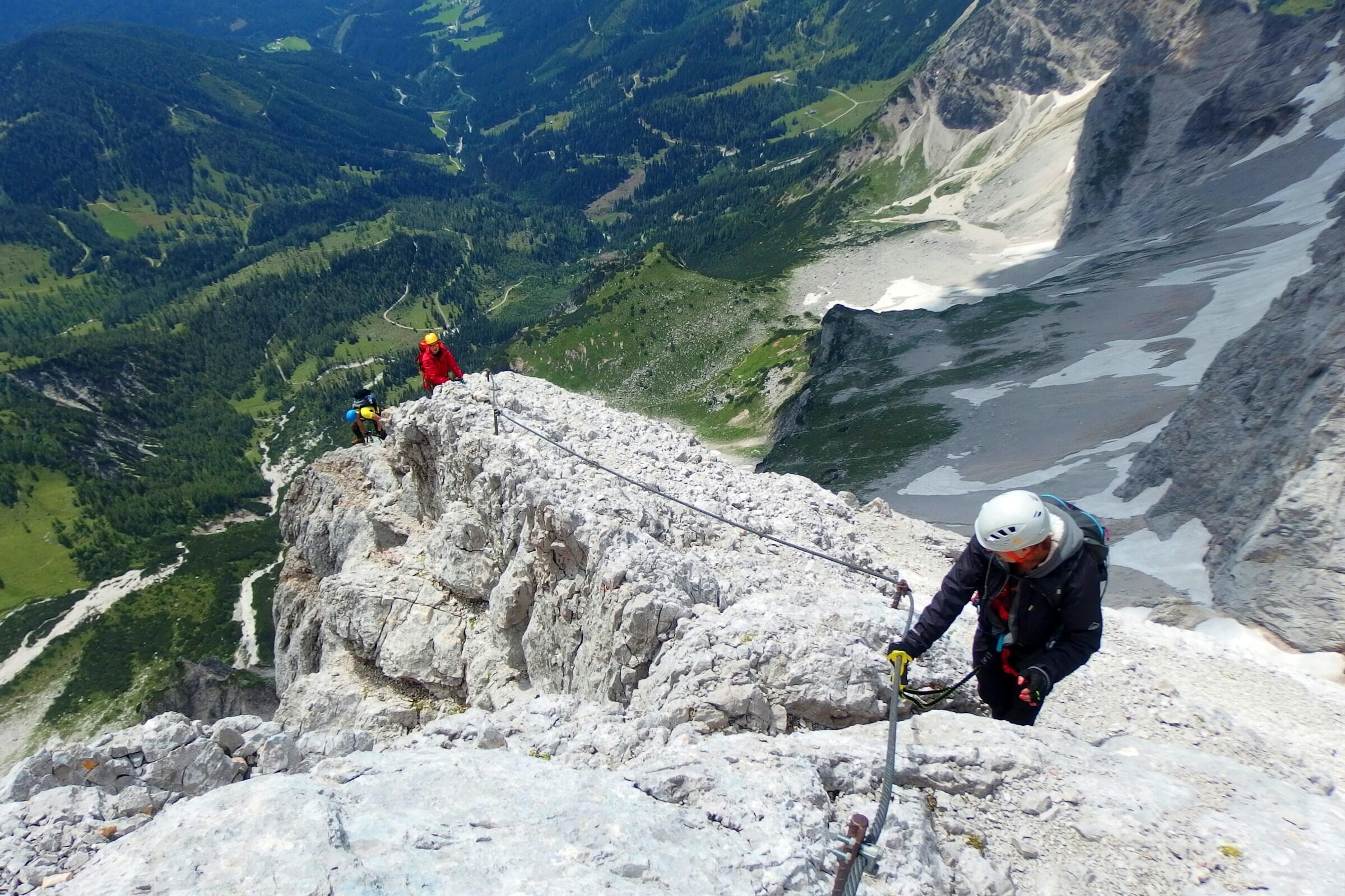 Climber on a rocky ridge above alpine valleys